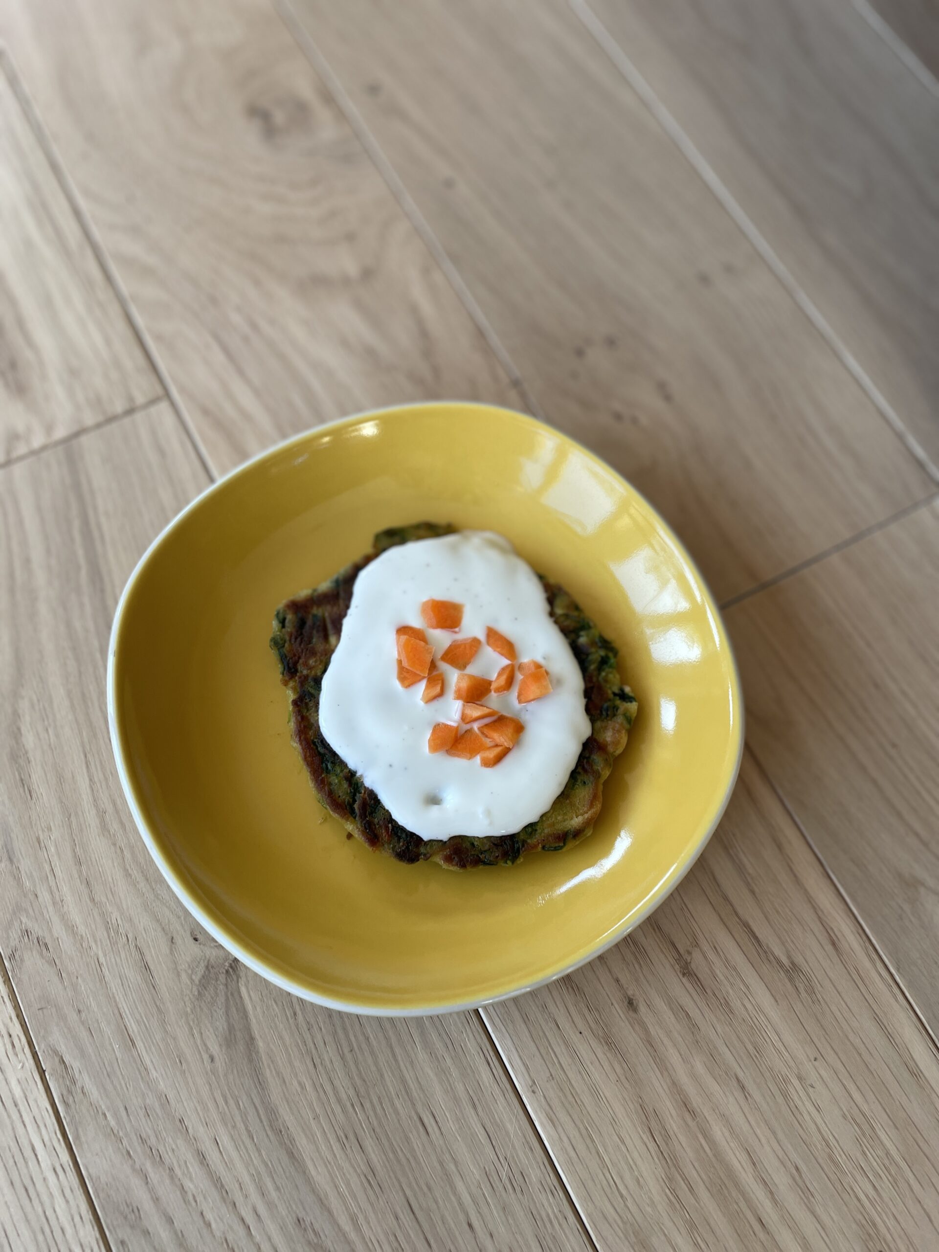 Photo d'un blini aux épinards, surmonté d'une sauce au yahourt et de dés de carotte